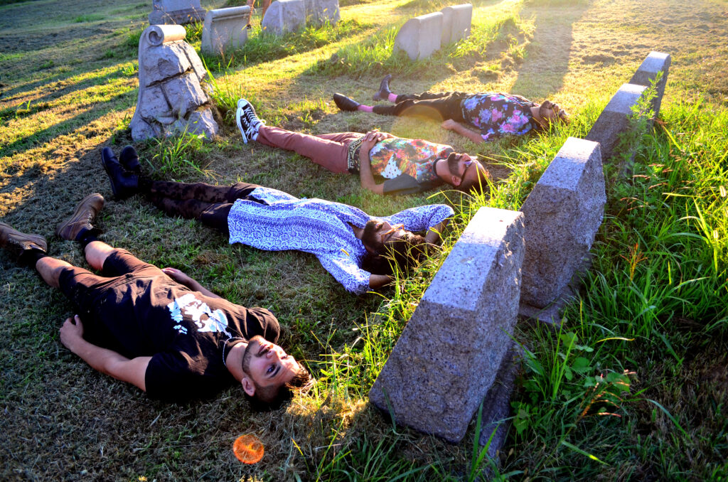 An image of Muslim punk band the Kominas lying down on the grass in a graveyard.