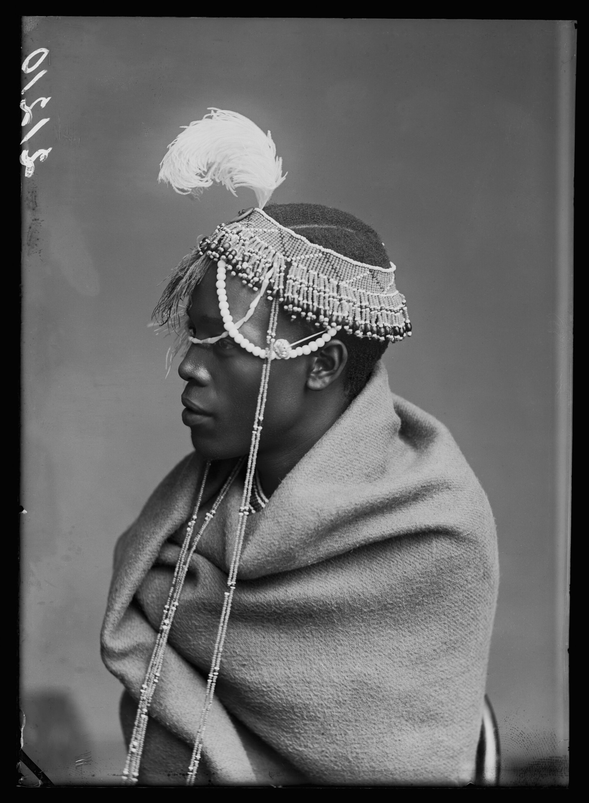 A studio portrait in black and white of a man wearing traditional dress, looking off to the right