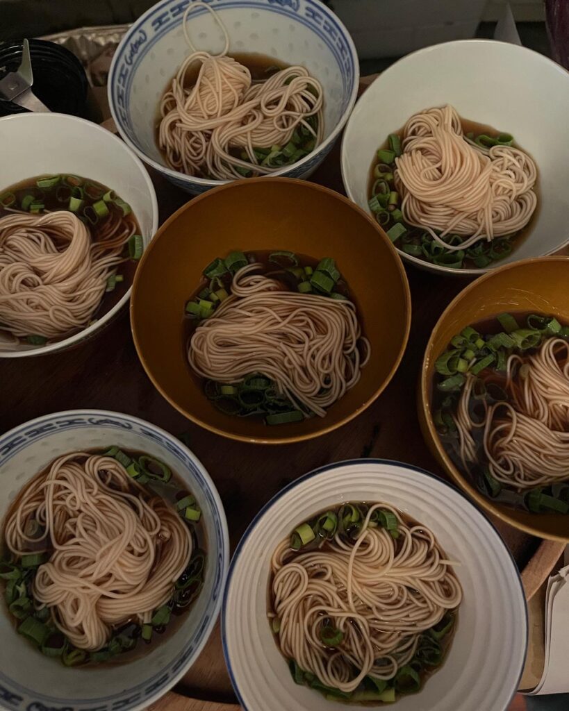 A photograph of bowls of noodles in sauce and with chopped spring onion, taken from above