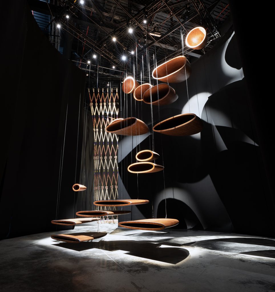 A photograph of an art installation, where several circular shapes are suspended in air on strings 